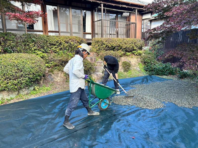 一輪車で玉砂利を敷く職人
